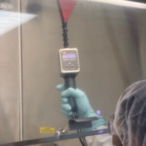 Gloved hand holding measuring device in lab